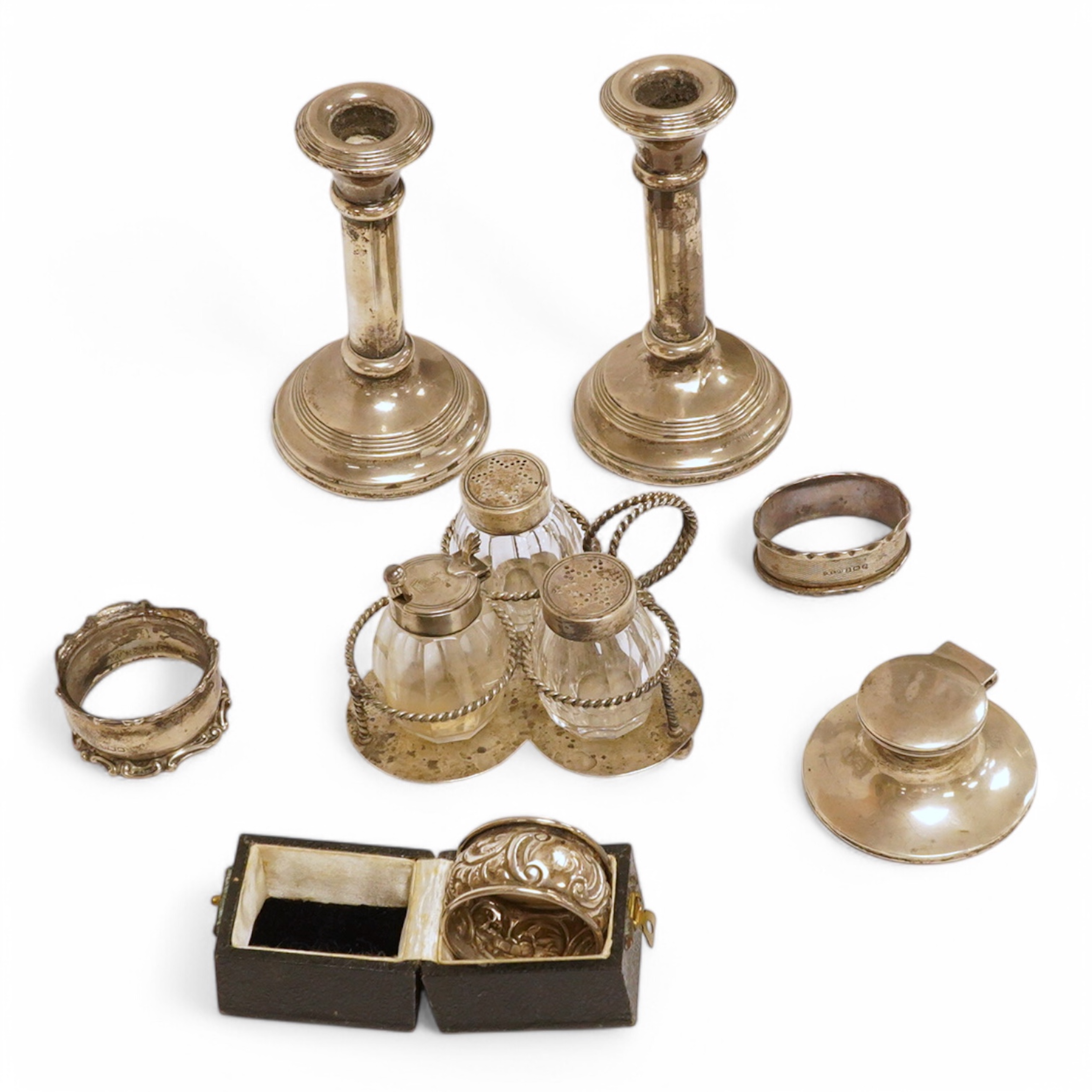 A late Victorian silver small cruet stand, with three mounted glass bottles, all Hukin & Heath, Birmingham, 1897, one associated bottle London, 1891, diameter 10.9cm, together with three assorted silver napkin rings, a s